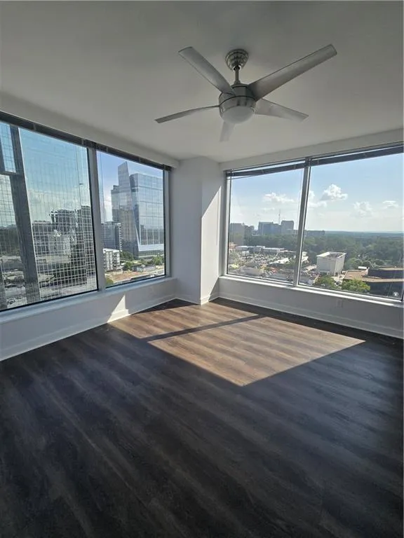 Unfurnished room featuring a view of city, wood finished floors, and a ceiling fan