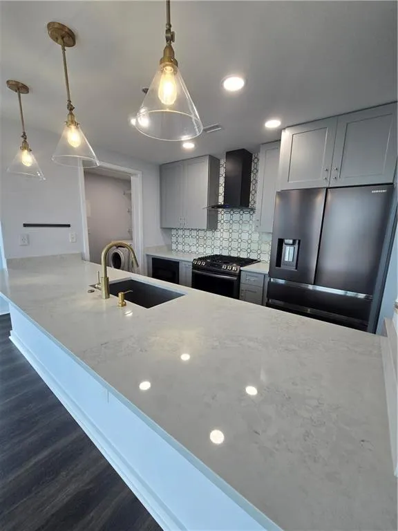 Kitchen featuring refrigerator, stainless steel range oven, exhaust hood, dark wood-style flooring, and backsplash
