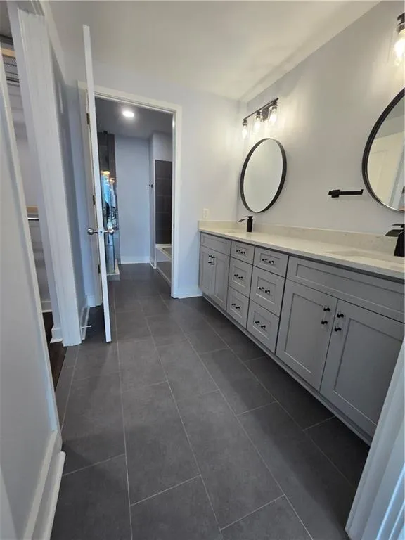 Bathroom featuring double vanity, tile patterned flooring, and a spacious closet