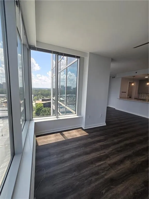 Spare room with dark wood-style flooring and baseboards