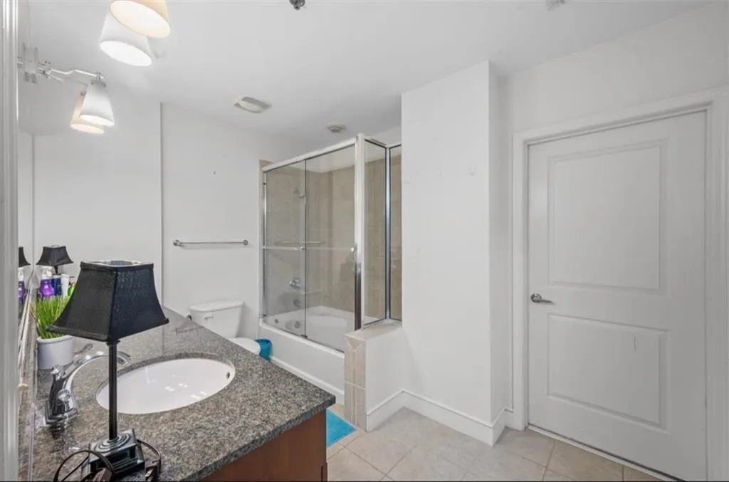 Full bath with vanity, combined bath / shower with glass door, and light tile patterned floors