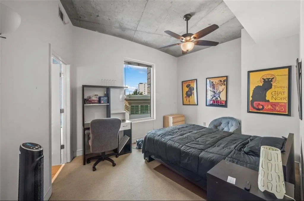 Carpeted bedroom with ceiling fan and an office area