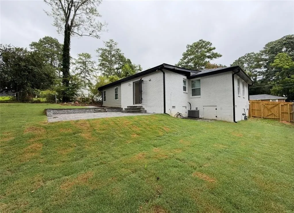 Rear view of house with brick siding, a patio, entry steps, and a gate