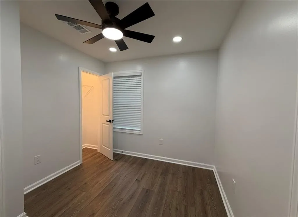 Unfurnished bedroom with a spacious closet, dark wood-type flooring, ceiling fan, and recessed lighting