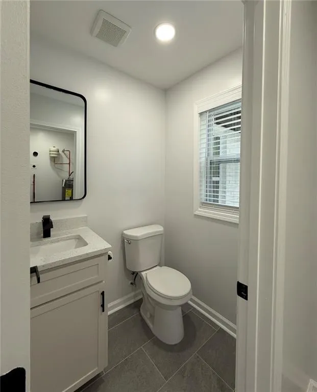 Half bath with vanity and dark tile patterned floors