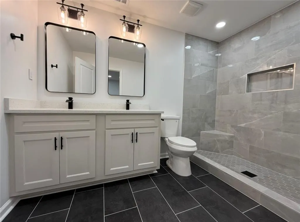 Full bath with a tile shower, dark tile patterned flooring, and recessed lighting