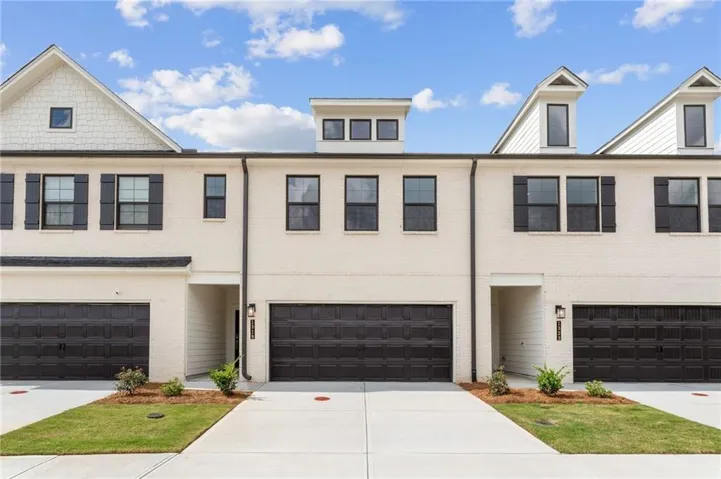 Brick facade with black shutters, dormer windows, and a two-car garage