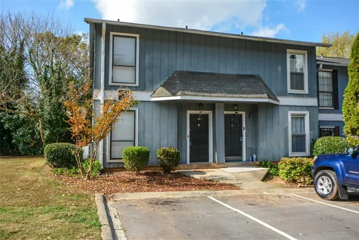 Two-story facade with vertical siding, gabled entry porch, and individual entry doors