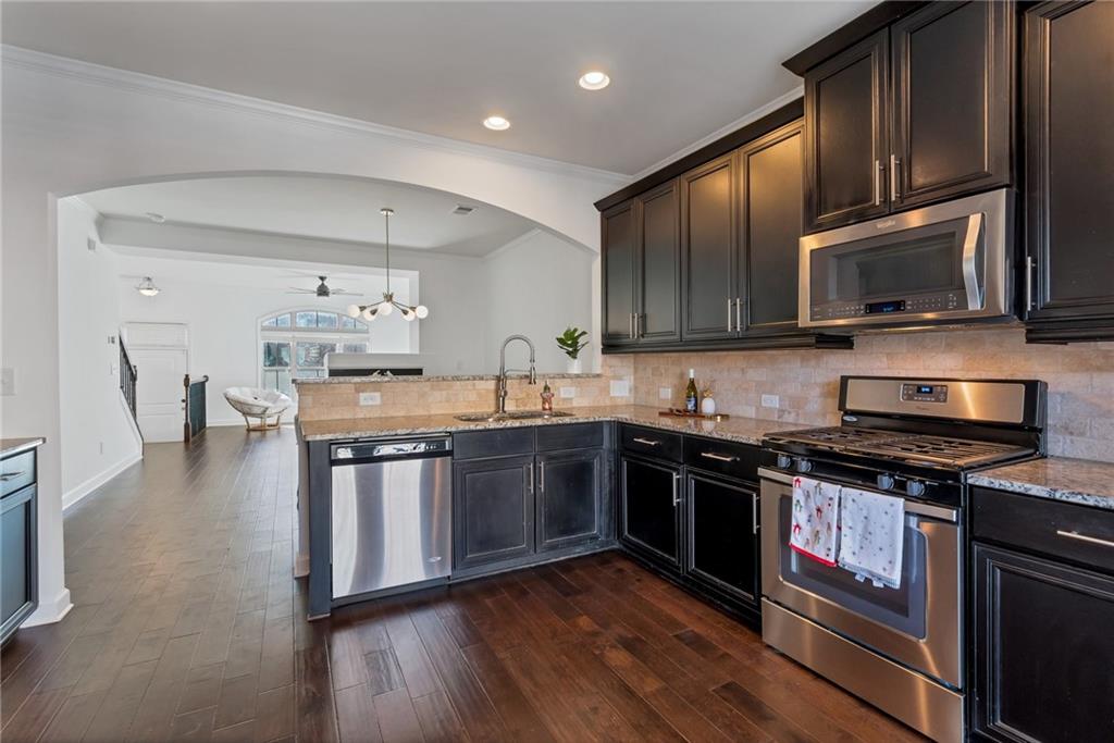 Kitchen featuring granite countertops, stone tile backsplash, and stainless steel appliances Kitchen featuring granite countertops, stone tile backsplash, and stainless steel appliances