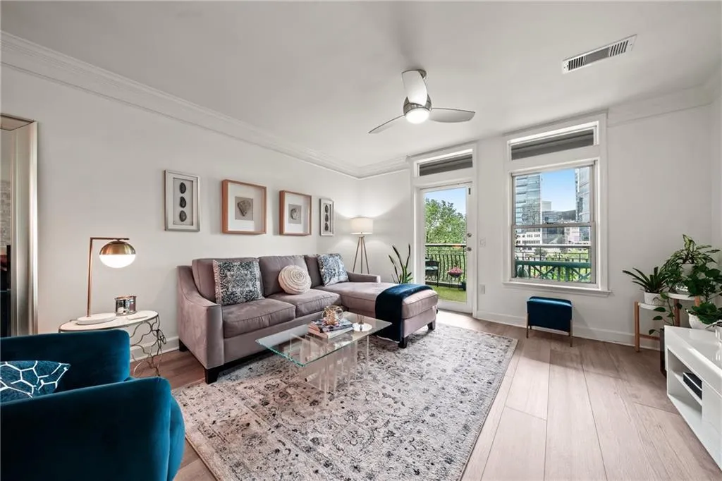 Bright living space featuring wood-finish flooring, crown molding, and a ceiling fan