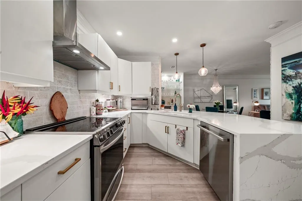 Contemporary kitchen featuring white cabinetry with brushed brass hardware, white subway tile backsplash, and quartz countertops
