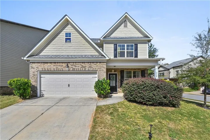 Two-story residence featuring a brick and siding exterior, a two-car garage, and a covered front porch
