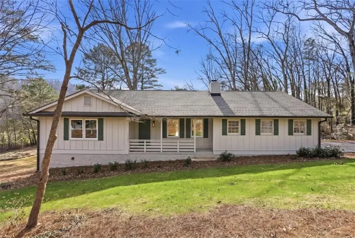 Ranch-style residence featuring white vertical siding, dark green window shutters, a covered front porch with white railing, and a gray shingle roof