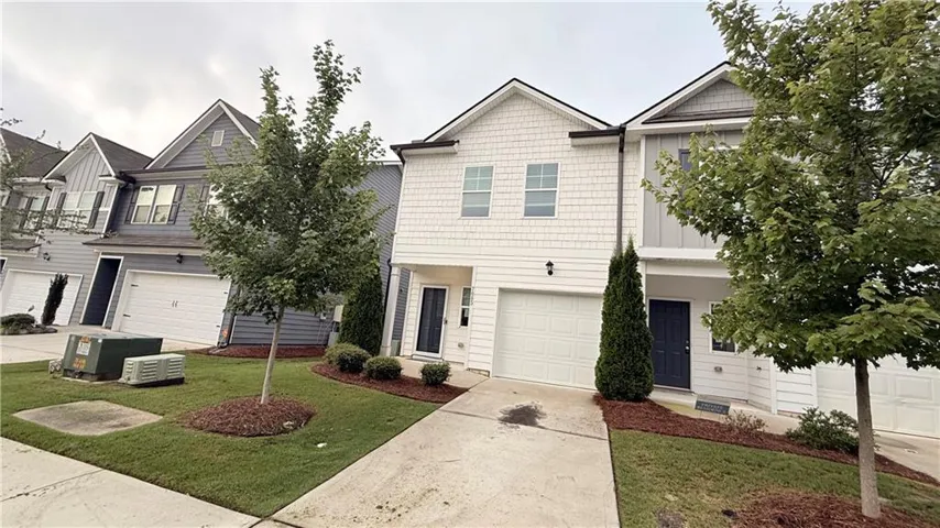 Shaker shingle siding and horizontal panel siding exterior with a single-car garage, established landscaping, and a paved driveway