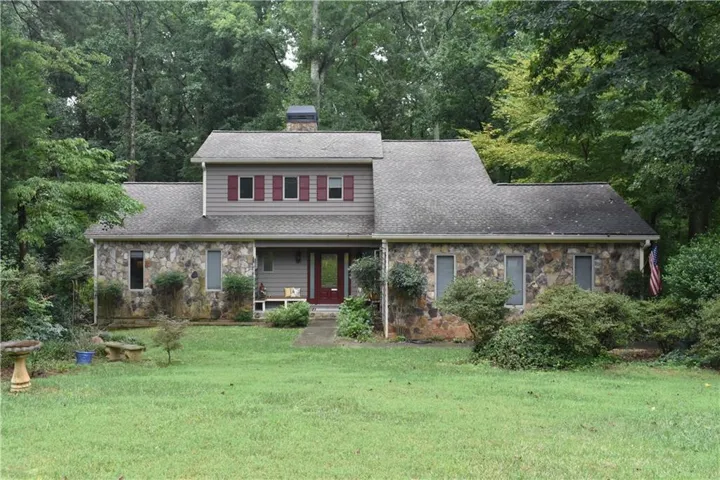 Stone and siding exterior with a prominent red entry door and red window shutters