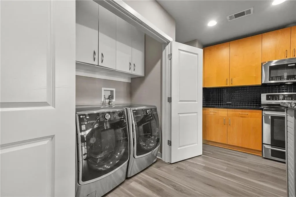 Laundry room featuring light wood finished floors, independent washer and dryer, recessed lighting, and cabinet space Laundry room featuring light wood finished floors, independent washer and dryer, recessed lighting, and cabinet space