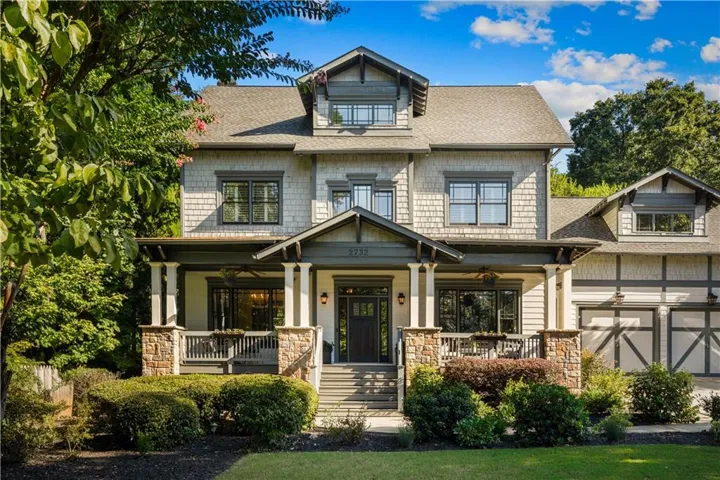 Craftsman-style residence with a covered front porch, stone column bases, shingle siding, and a multi-level roofline