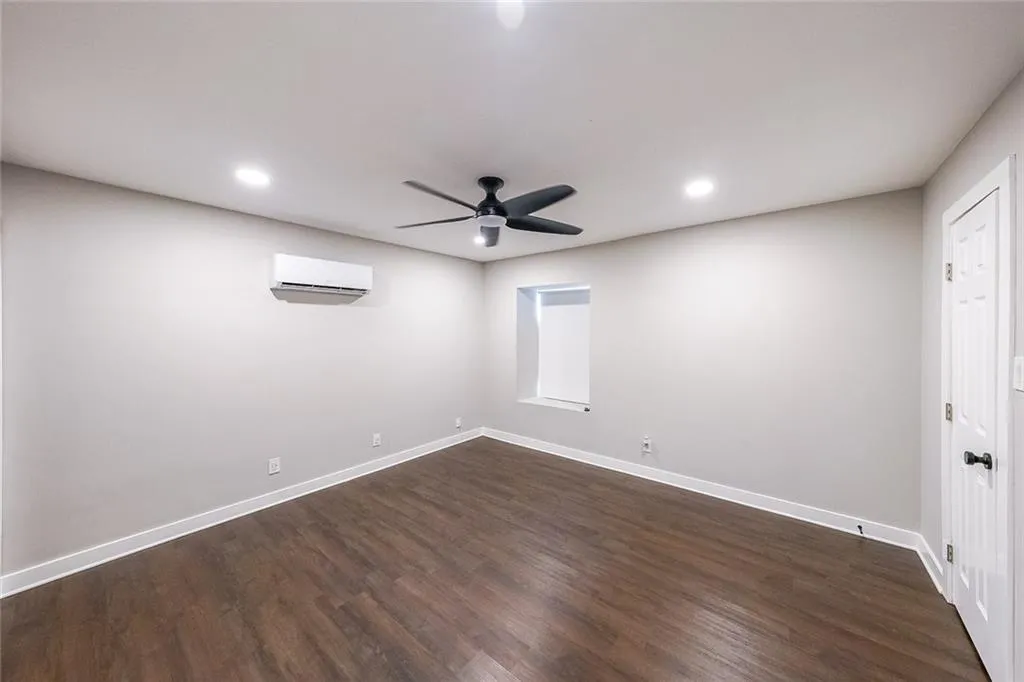 Empty room featuring dark wood-style floors, a ceiling fan, baseboards, recessed lighting, and a wall mounted air conditioner
