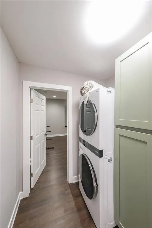 Washroom with baseboards, dark wood-style floors, laundry area, and stacked washer / dryer
