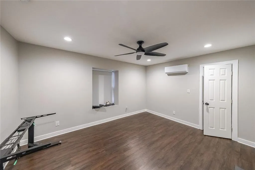 Workout room featuring baseboards, dark wood-type flooring, a ceiling fan, and a wall mounted AC