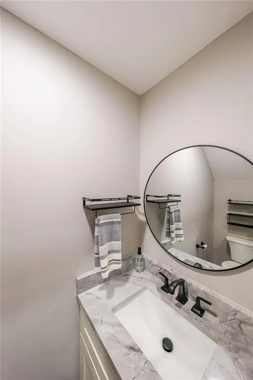 Half bath featuring marble finish floor, vanity, and toilet