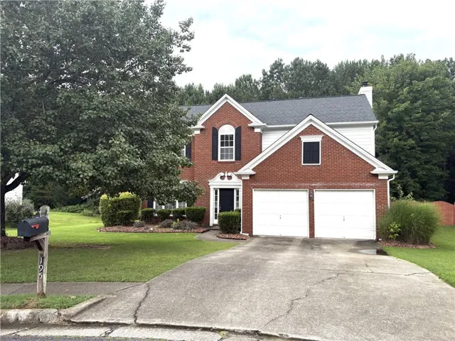 Traditional two-story residence featuring a brick and white siding exterior