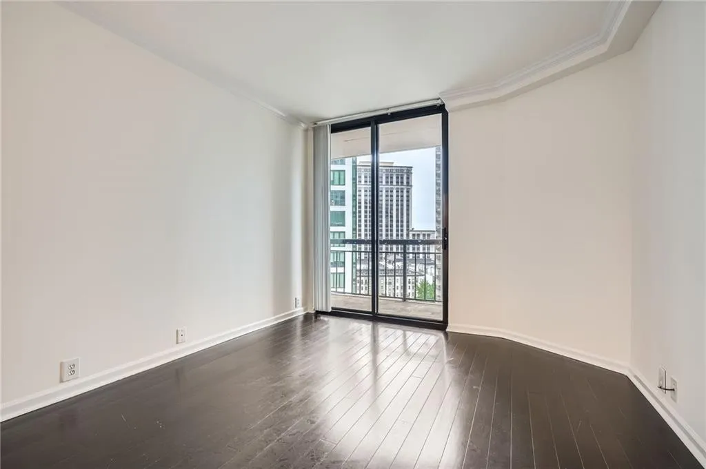 Unfurnished room featuring floor to ceiling windows, baseboards, crown molding, and dark wood-type flooring