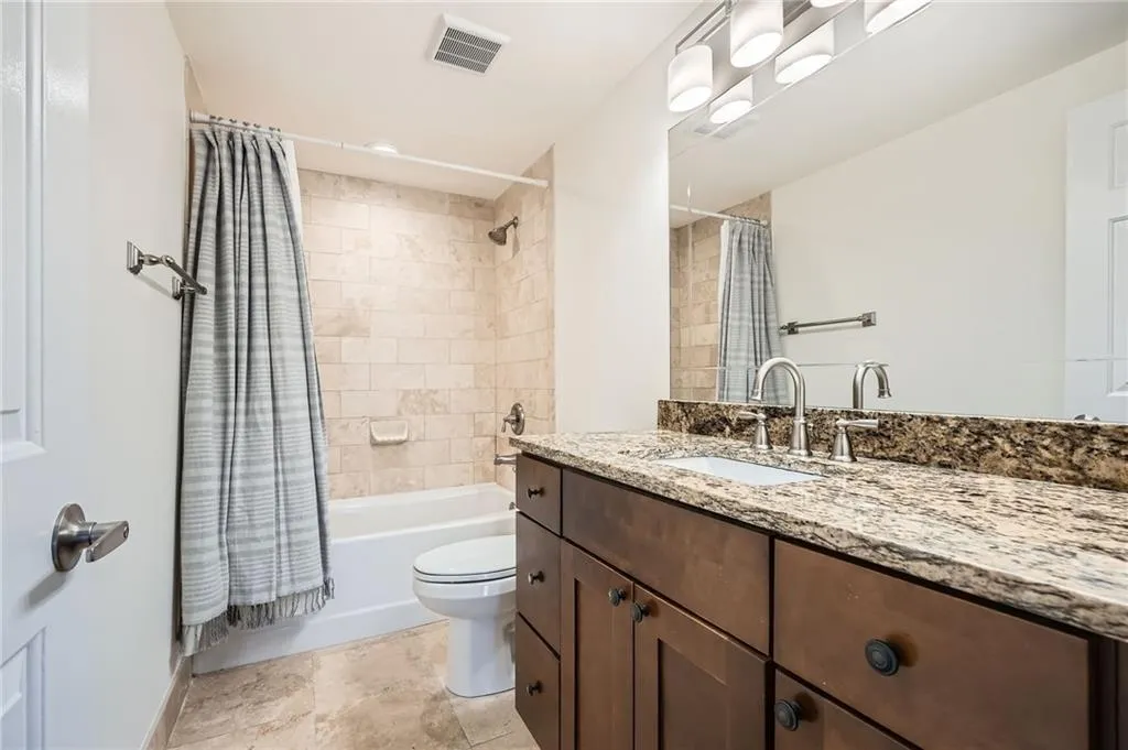 Full bath featuring toilet, shower / bath combo with shower curtain, vanity, and visible vents