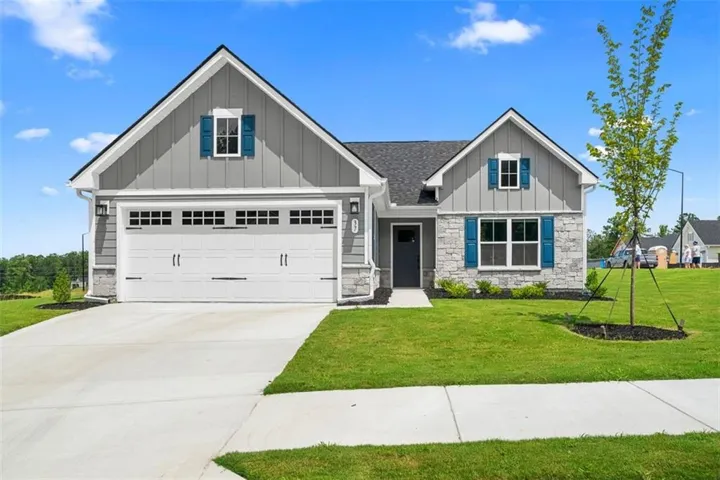 Gray siding exterior with stone accents, a two-car garage with transom windows, and vibrant blue shutters