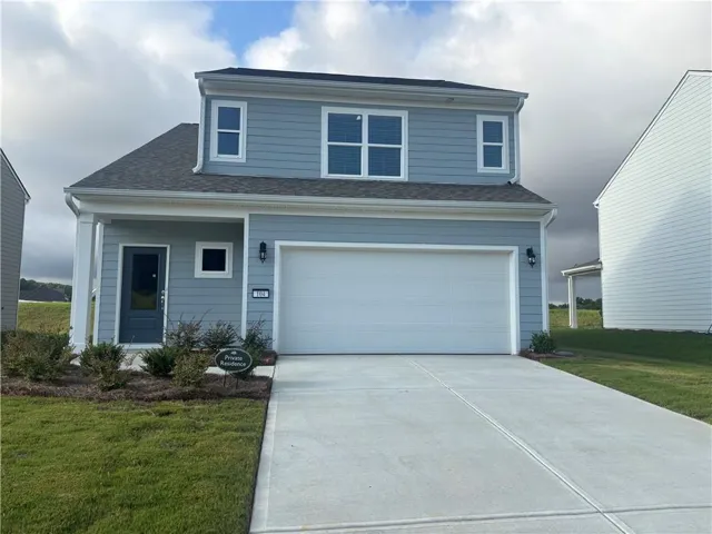 Traditional-style house with driveway, a garage, and a front lawn