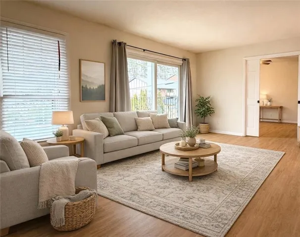Expansive living area with wood-finish flooring, sliding glass door, and recessed wall paneling