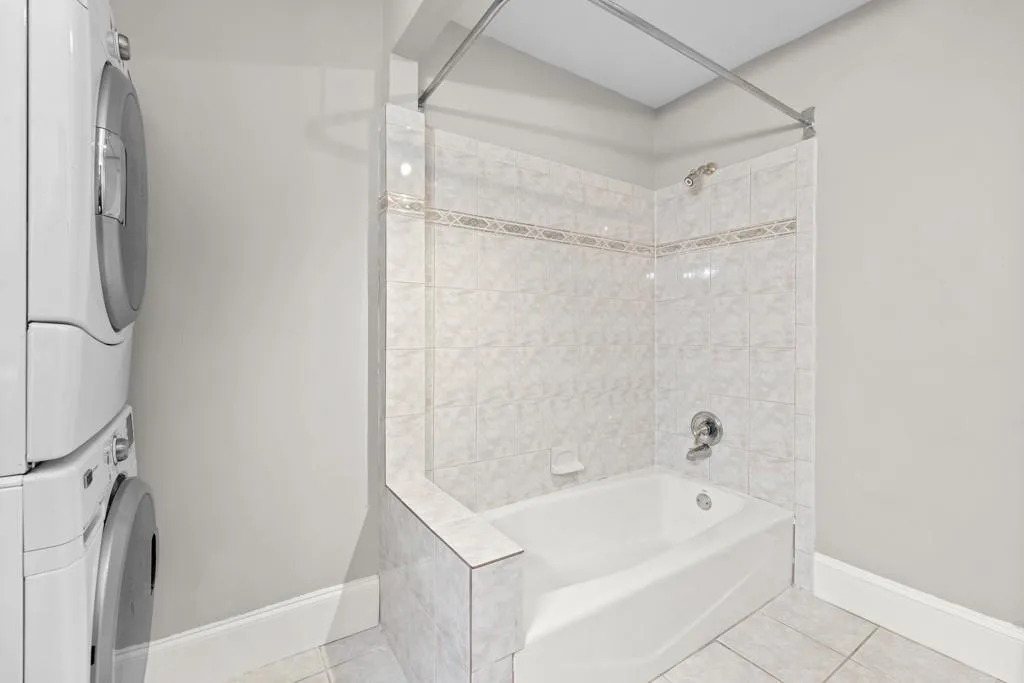 Bathroom featuring tile patterned floors, tiled shower / bath, and stacked washer / drying machine