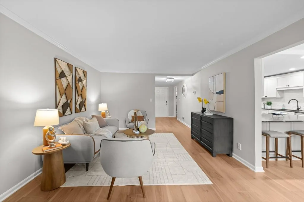 Living room with ornamental molding, sink, and light hardwood / wood-style floors