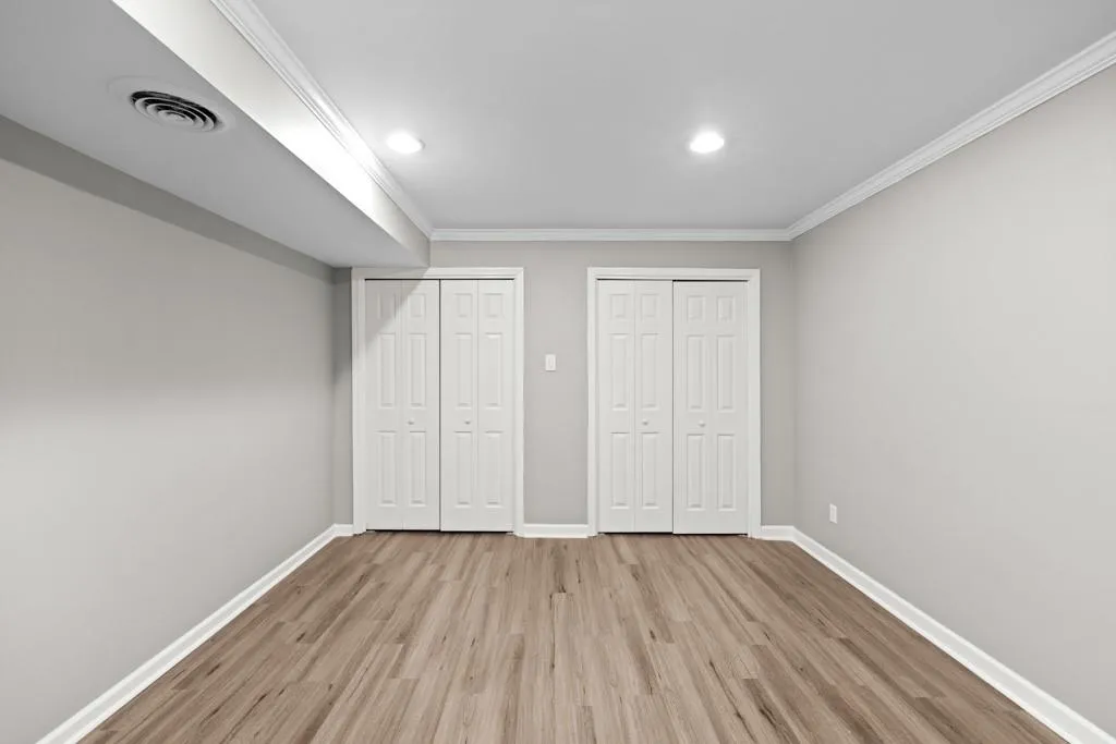 Unfurnished bedroom featuring ornamental molding, multiple closets, and light hardwood / wood-style flooring