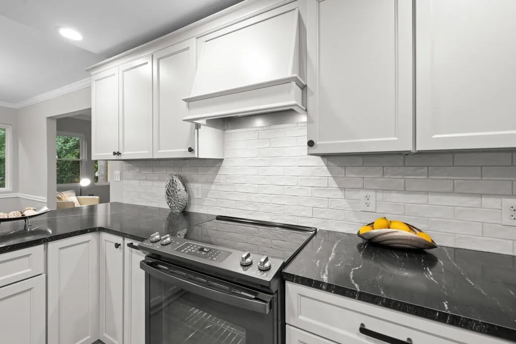 Kitchen featuring ornamental molding, dark stone countertops, electric range, and white cabinets