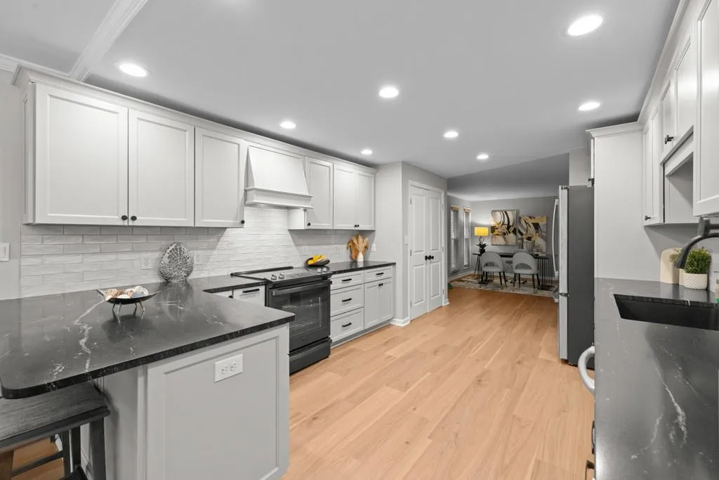 Kitchen featuring white cabinets, electric range oven, dark stone counters, and light hardwood / wood-style flooring