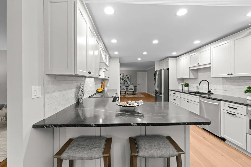 Kitchen featuring white cabinetry, stainless steel appliances, kitchen peninsula, sink, and light hardwood / wood-style floors