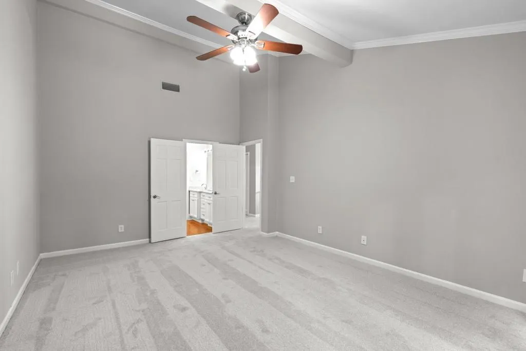 Carpeted empty room featuring ornamental molding and ceiling fan