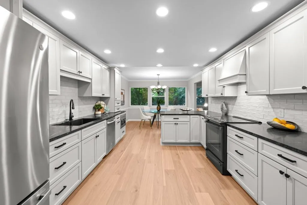 Kitchen with dark stone countertops, appliances with stainless steel finishes, sink, custom exhaust hood, and light wood-type flooring