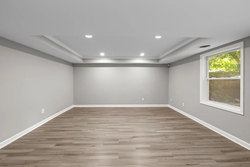 Empty room with crown molding, a raised ceiling, and hardwood / wood-style floors