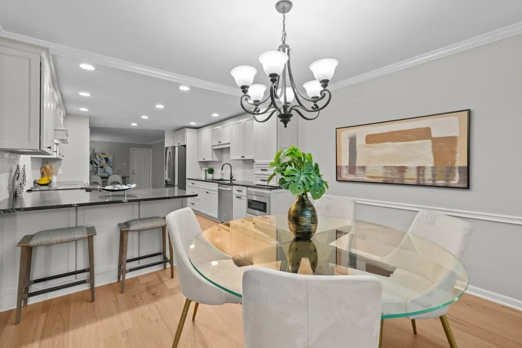 Dining area with light wood-type flooring, an inviting chandelier, crown molding, and sink