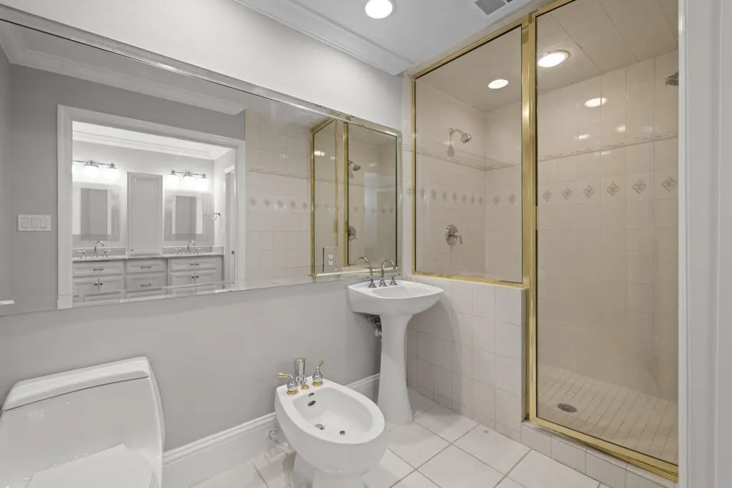 Bathroom featuring tile patterned flooring, crown molding, walk in shower, toilet, and a bidet
