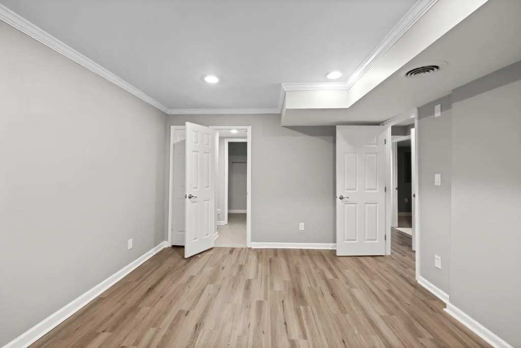 Unfurnished bedroom featuring ornamental molding, light hardwood / wood-style flooring, and a walk in closet