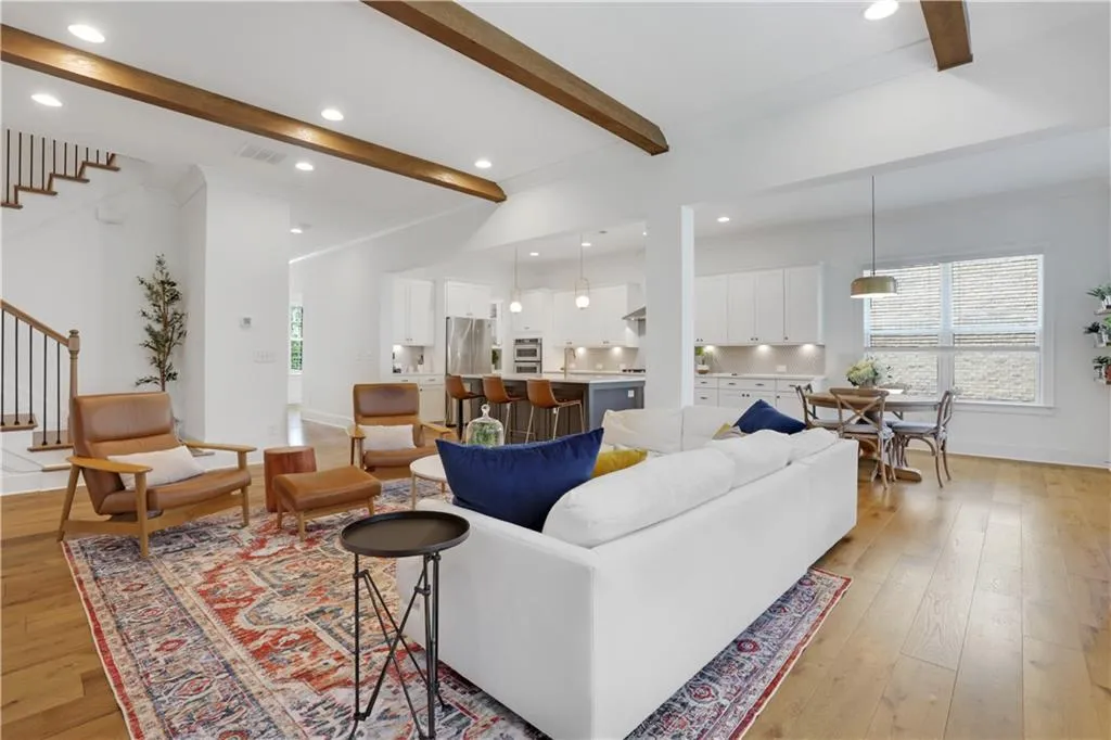 Open-concept living space with vaulted ceilings, exposed wood beams, and recessed lighting