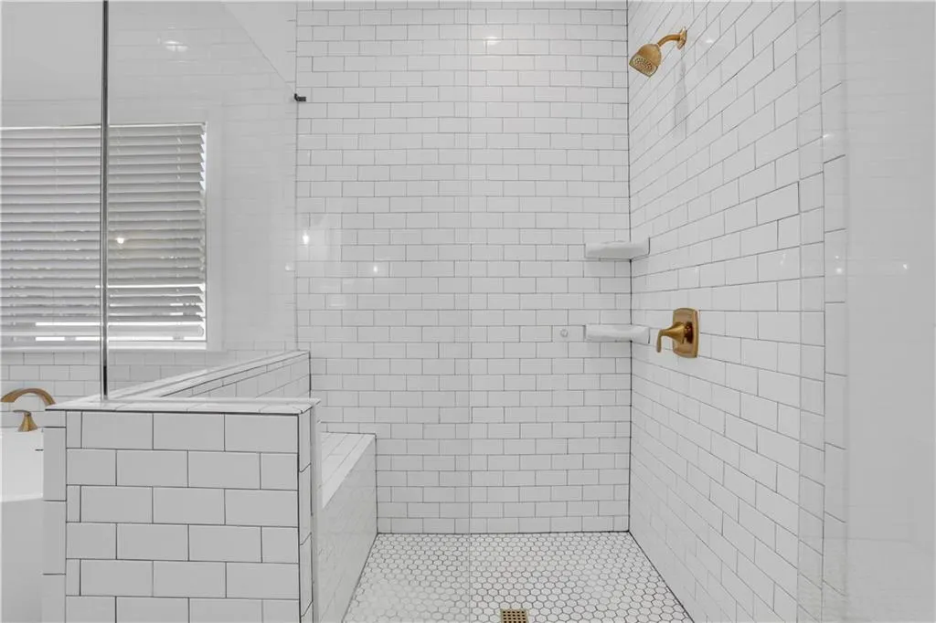 Walk-in shower featuring white subway tile, a built-in bench, and hexagonal floor tile