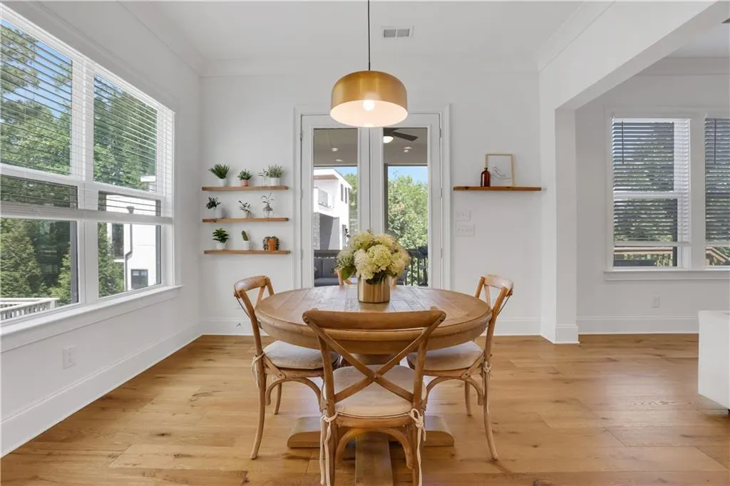 Dining area featuring wide plank wood-finish flooring, a contemporary overhead light fixture, and abundant natural light from multiple windows
