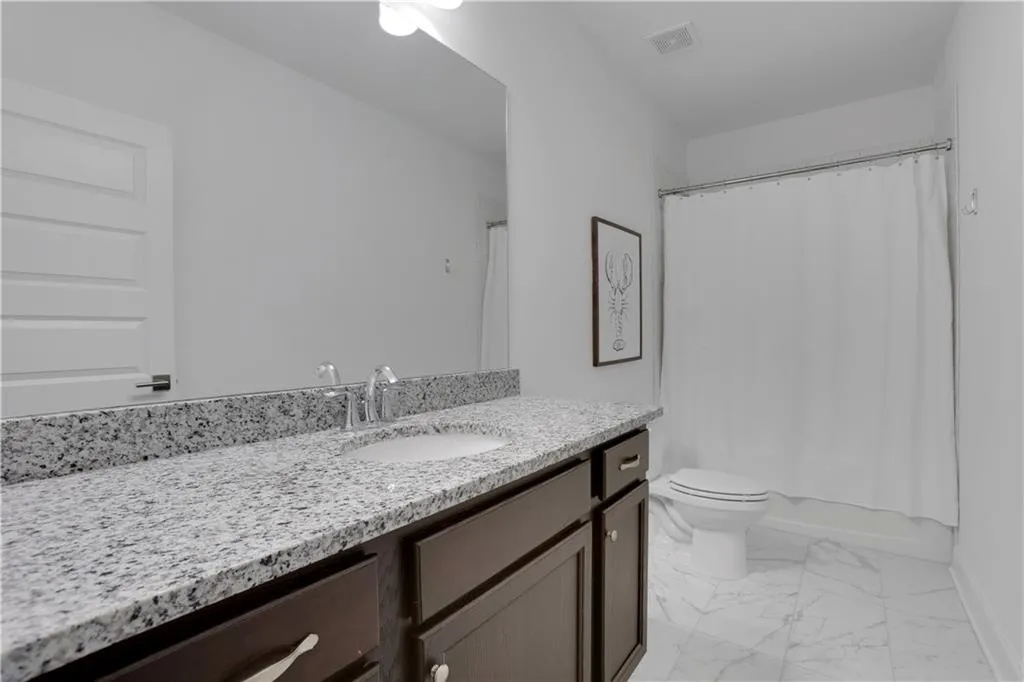 Bathroom featuring a granite vanity with an undermount sink, dark wood cabinetry, polished chrome fixtures, and a shower/tub combination