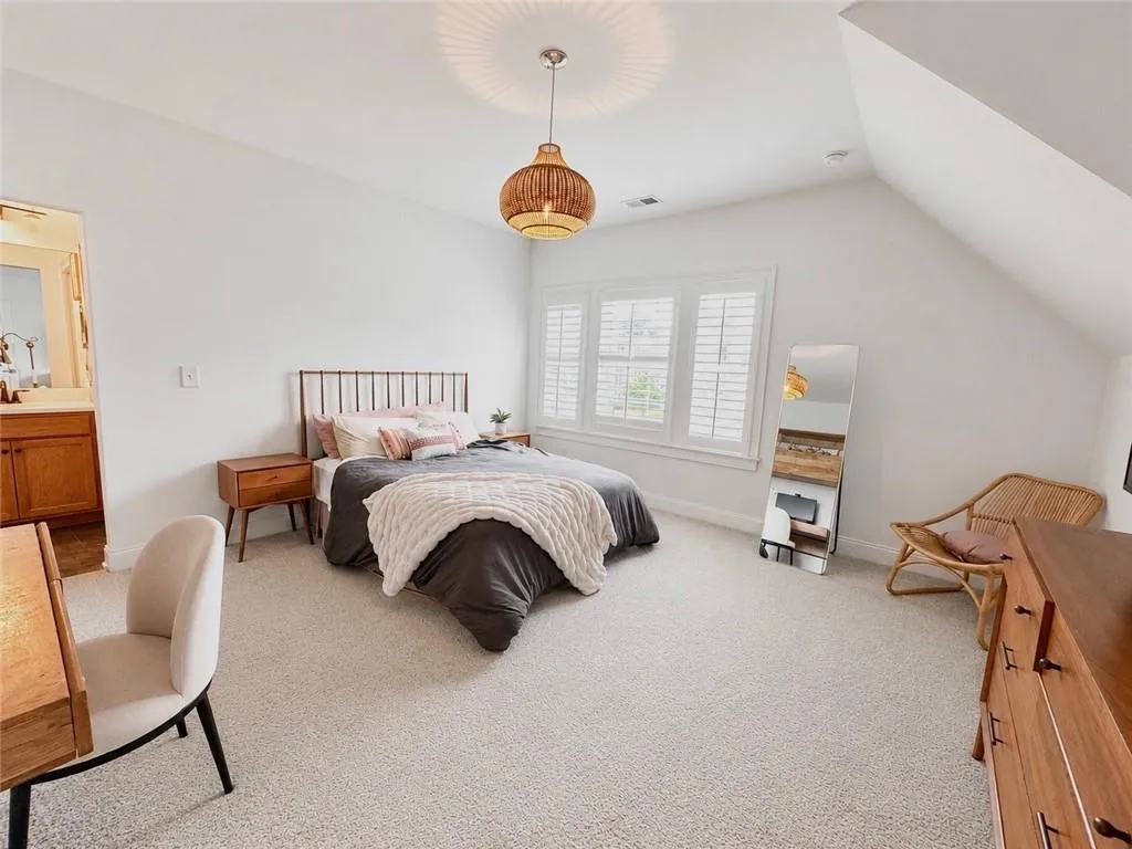 Bright room featuring white walls, light-colored carpeting, and a sloped ceiling with a pendant light fixture