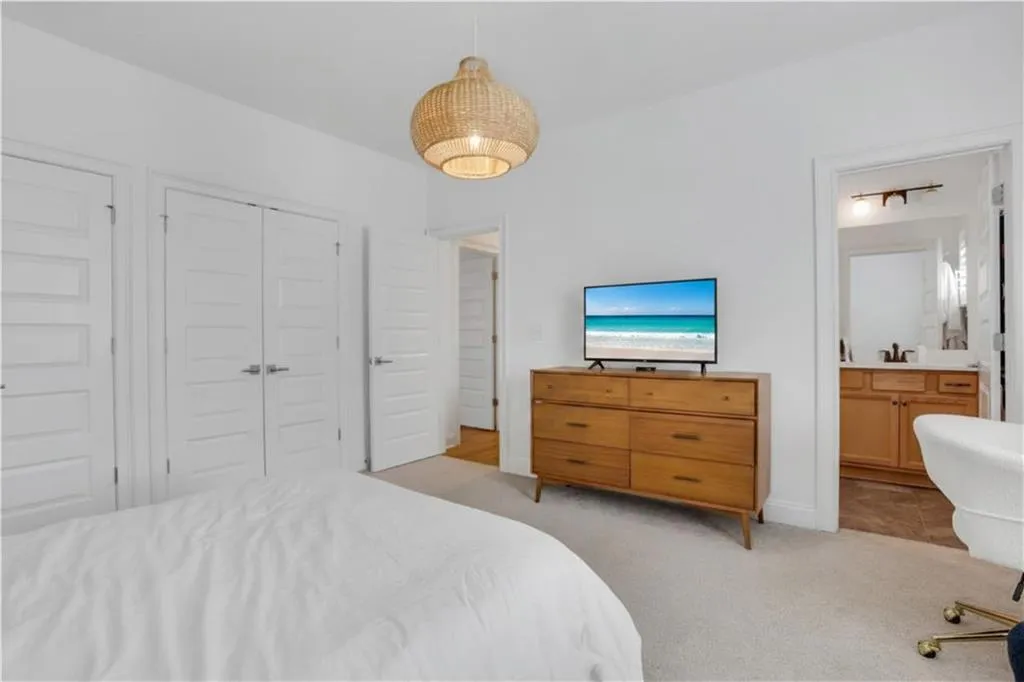 Bedroom featuring light-colored carpet flooring and a woven pendant light fixture
