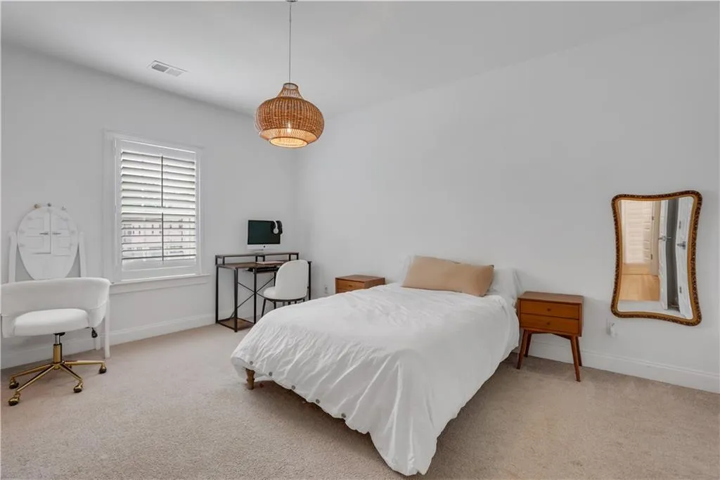 Carpeted room with a ceiling-mounted woven light fixture, white walls, and white window shutters